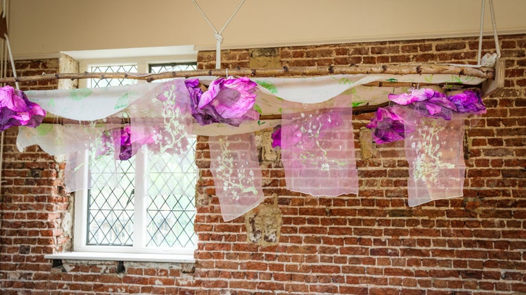 Festival of Blossom community canopy of pink and white fabric suspended in front of a brick wall in the Orangery Café at Ham House London